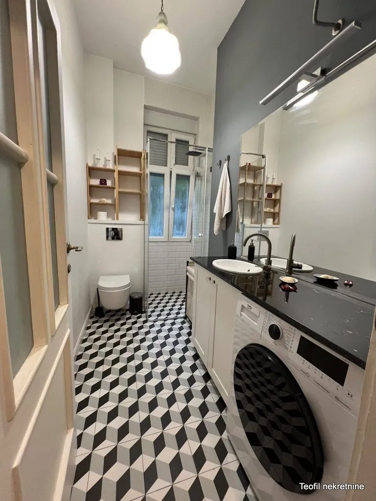 Modernly equipped bathroom with a washing machine and a shower cabin.