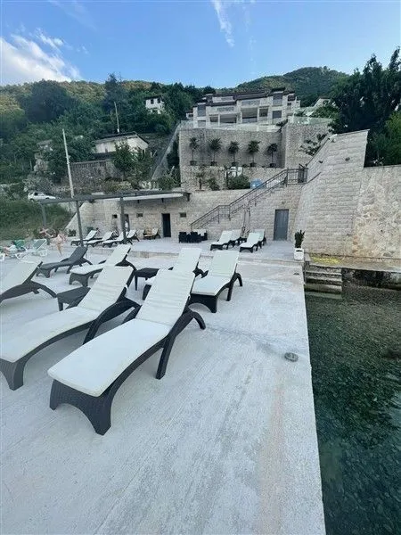Popločana terasa pored mora sa ležaljkama ispred kamene vile.