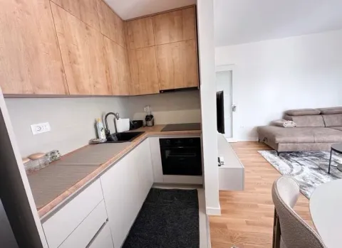 Kitchen with wooden cabinetry and a view of the living room. - image 6