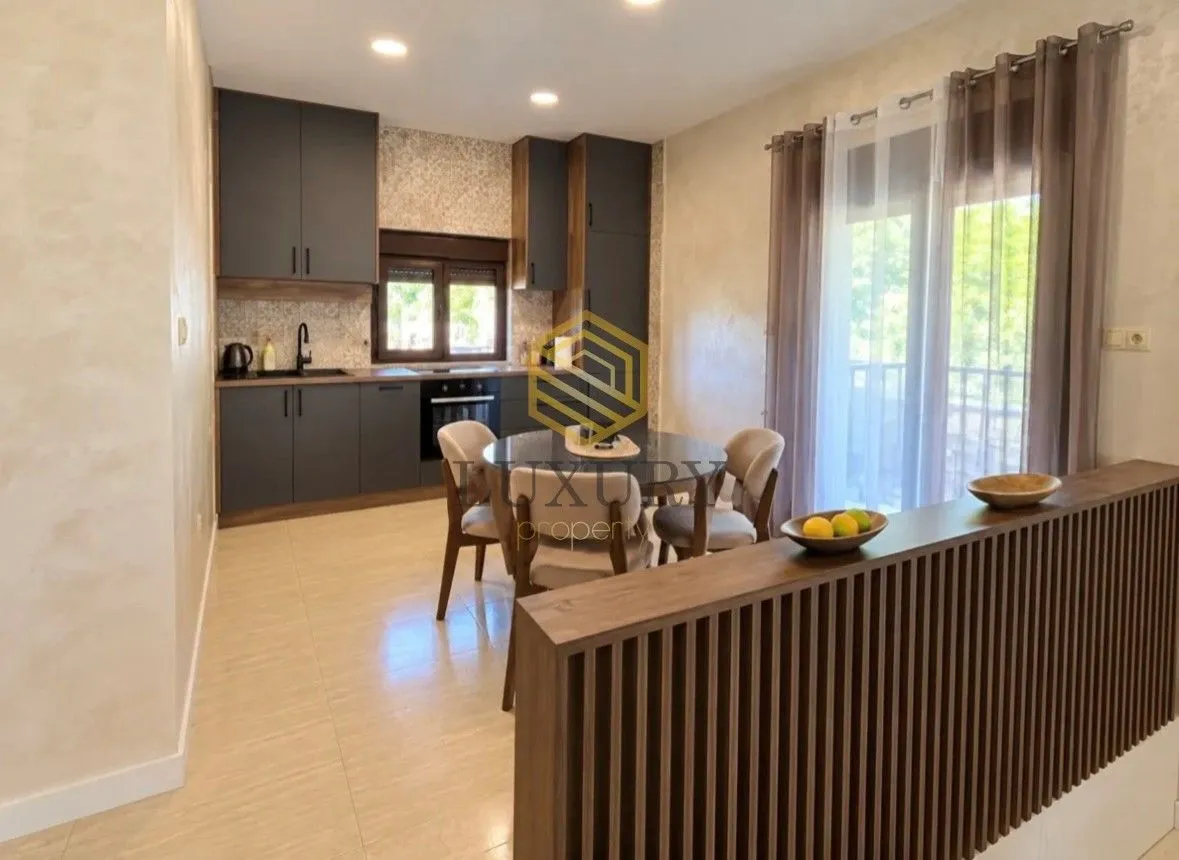 Modern kitchen with dining area and dark cabinetry.