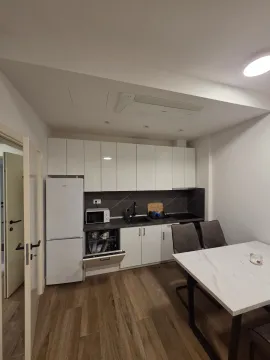 Moderna kuhinja sa bijelim elementima i trpezarijskim stolom. - image 3