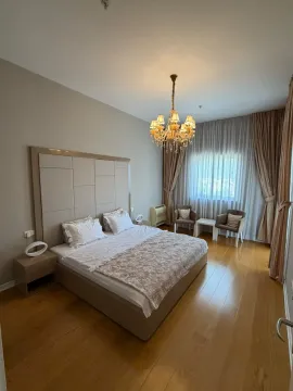 Spacious bedroom with a large double bed, upholstered headboard, and seating area. - image 2