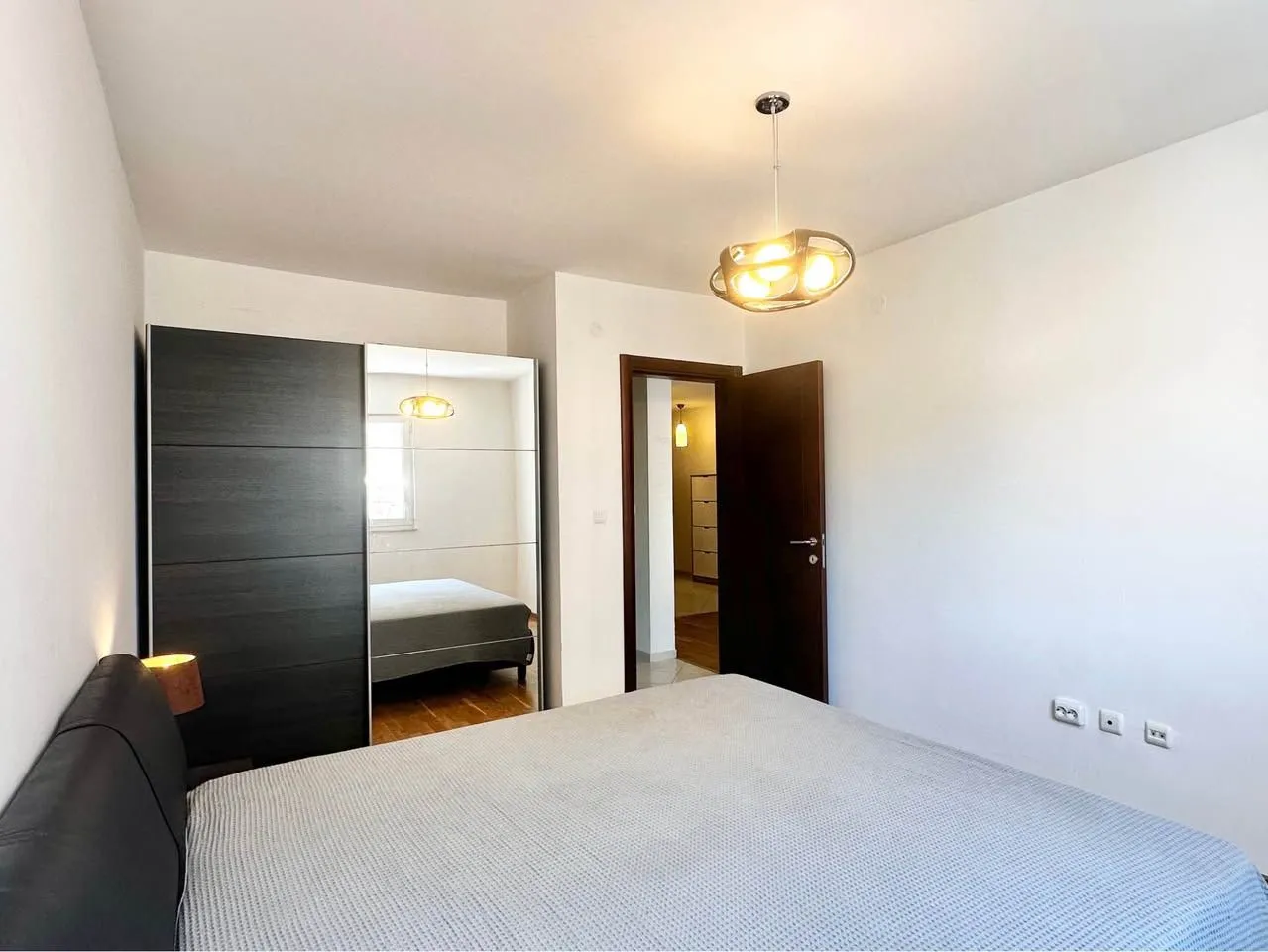 Furnished bedroom with a double bed, wardrobe, and a door leading to the hallway.
