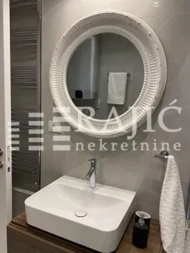 Modern bathroom with a sink and round mirror. - image 5