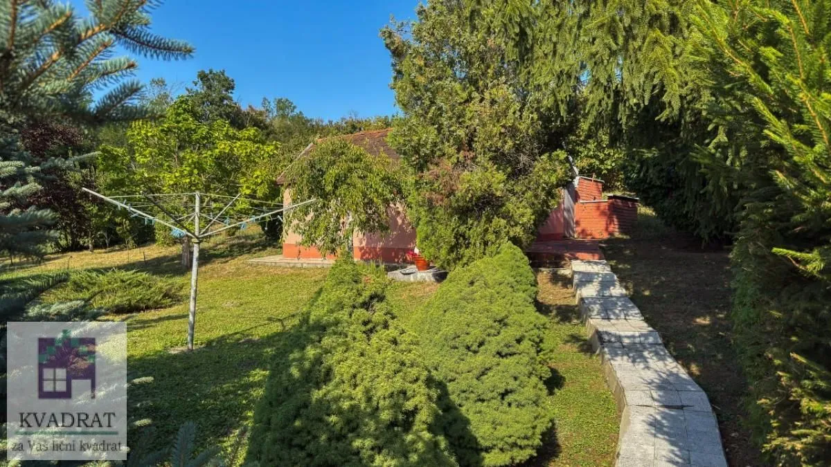 Pogled na zeleno dvorište i deo kuće okružene drvećem.