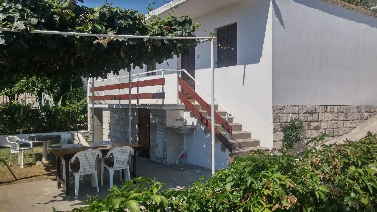 Eksterijer kuće sa dvorištem, spoljašnjim stepenicama i garniturom za sjedenje.