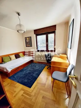 Furnished bedroom with a bed, desk, and parquet flooring. - image 4