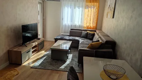 Bright living room with a corner sofa, TV, and a dining table. - image 2