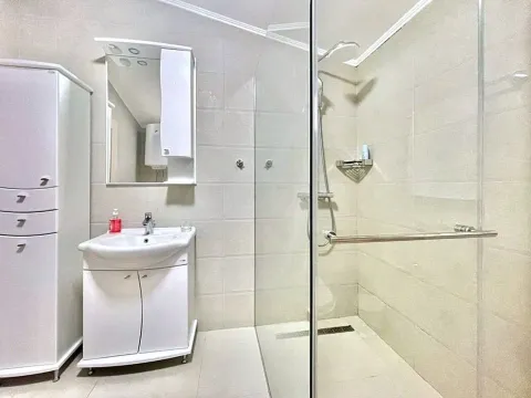 Kupatilo opremljeno umivaonikom, ogledalom, ormarićem i tuš kabinom. - image 3
