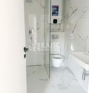 Modern bathroom with a walk-in shower and marble tiles. - image 5
