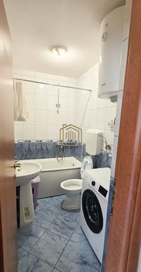 Small bathroom equipped with a bathtub, washbasin, toilet, and washing machine.