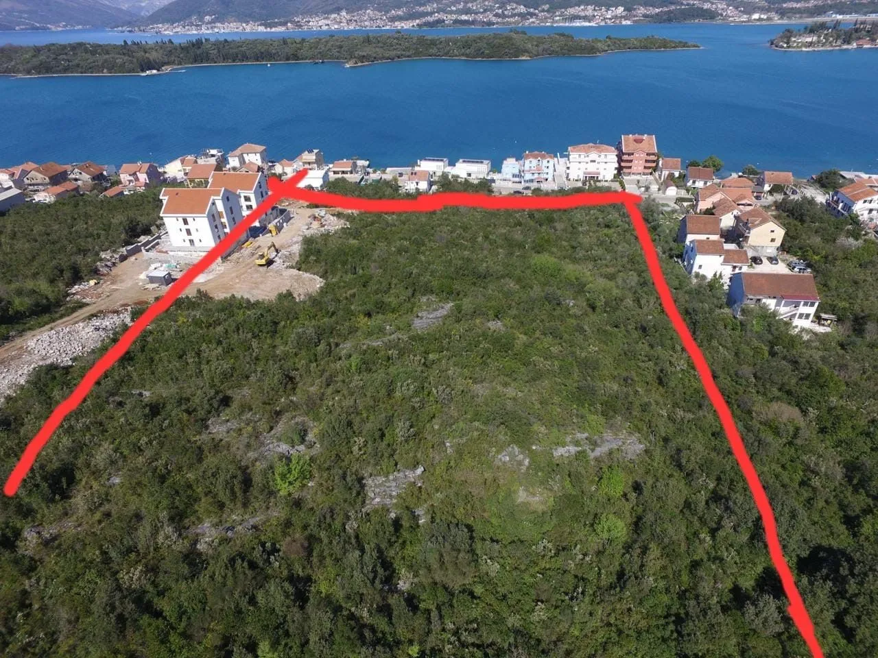 Vazdušni pogled na građevinsko zemljište sa ucrtanim granicama parcele pored mora.
