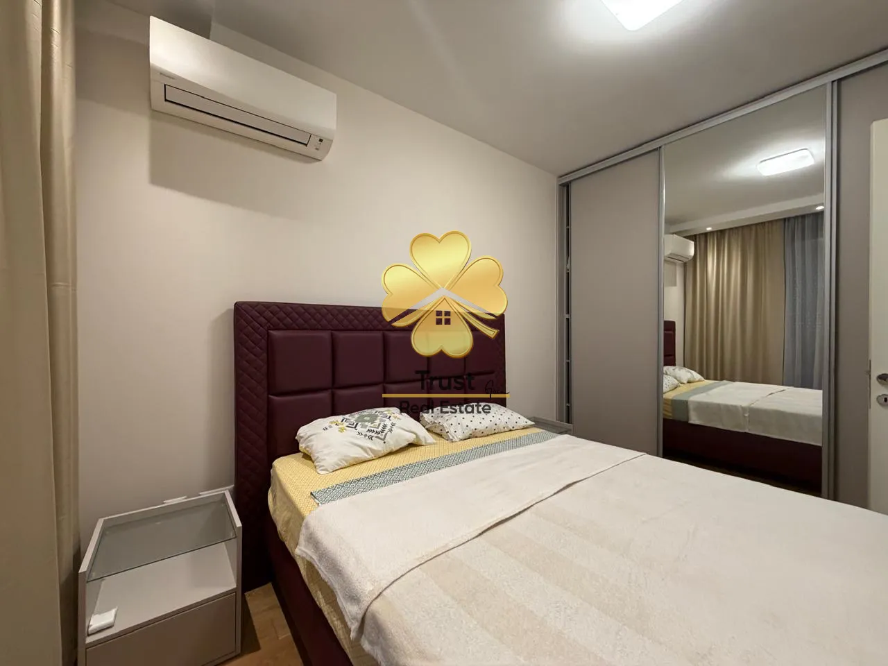 Furnished bedroom with a double bed and a built-in wardrobe with a mirror.