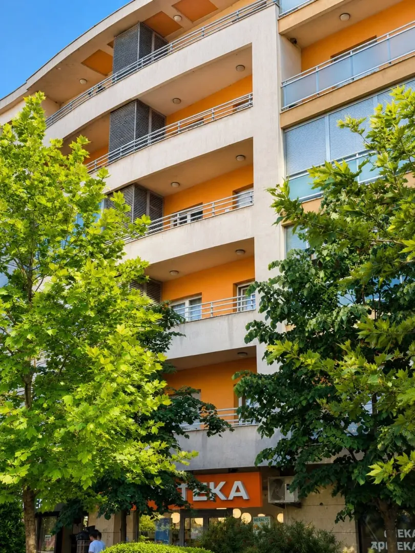 Exterior of a multi-family residential building with balconies and greenery in the foreground.