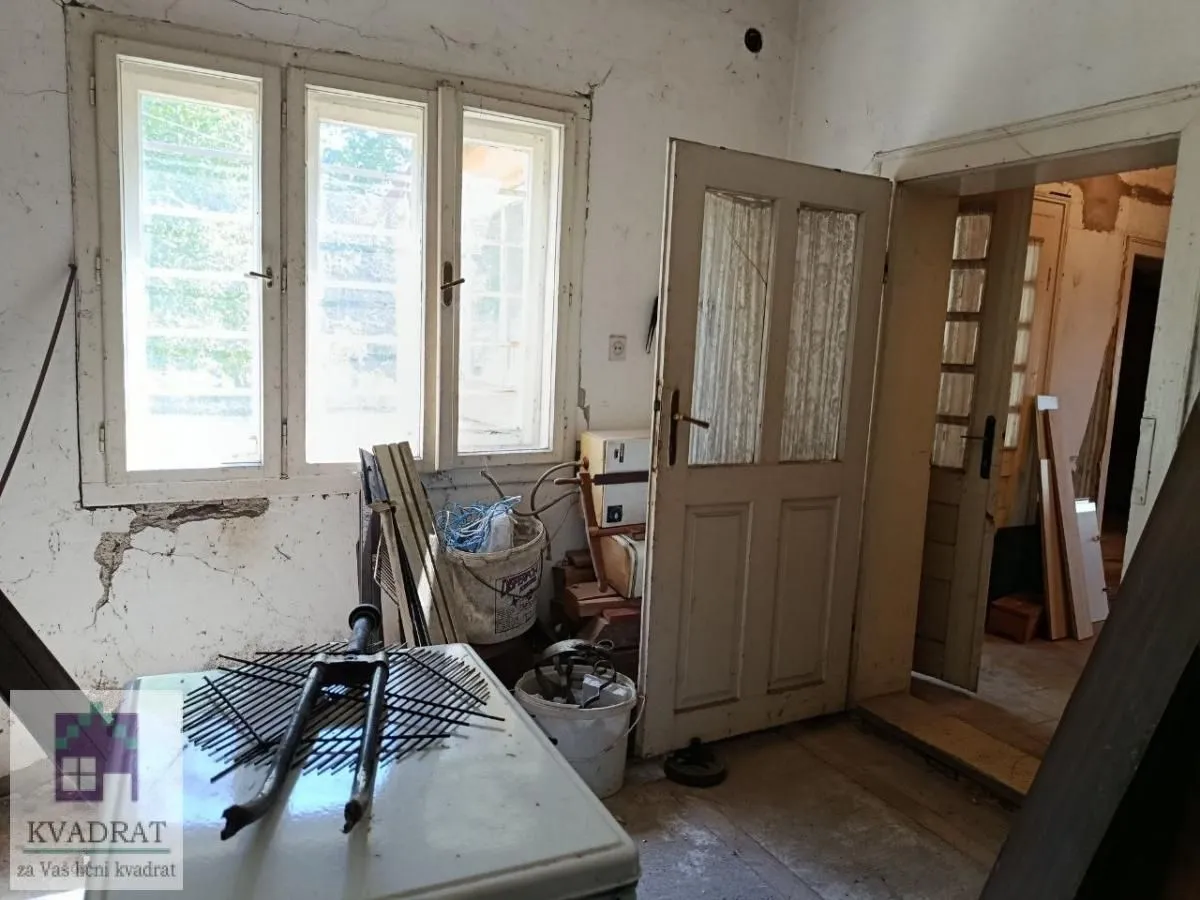 Prazna prostorija u kući za renoviranje sa starim prozorima i vratima.