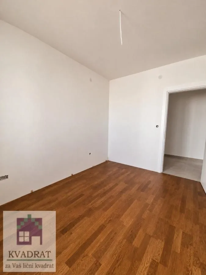 Empty room with wooden flooring and white walls.