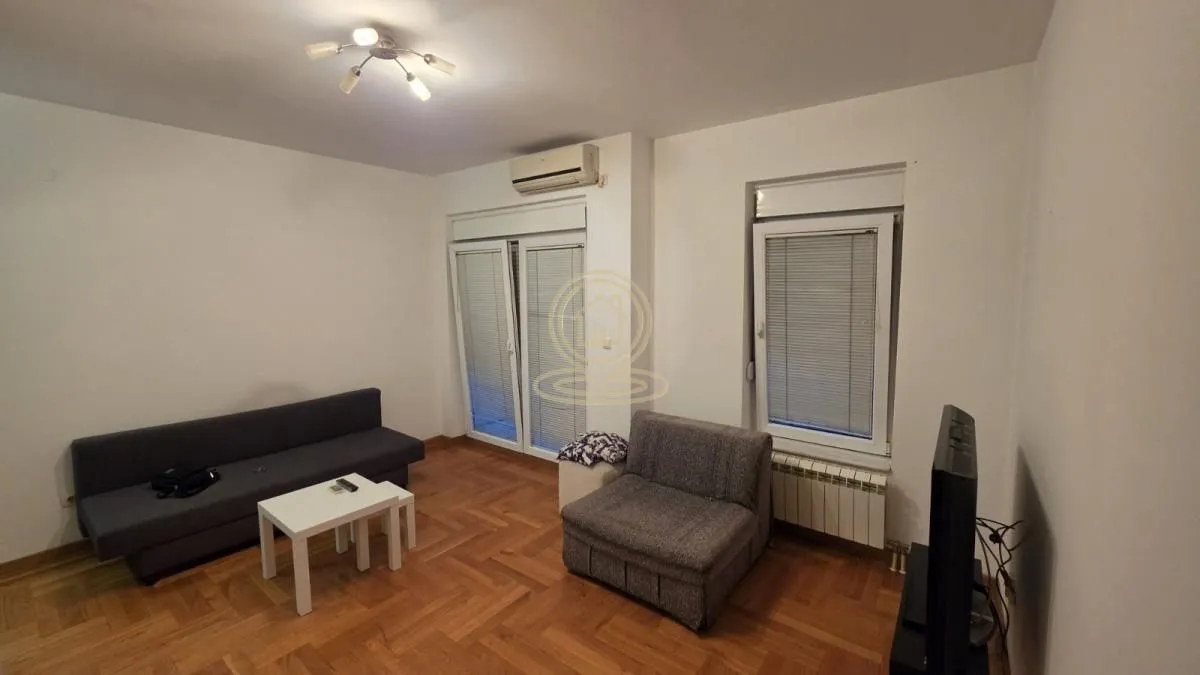Dnevna soba sa garniturom za sedenje, stočićem i televizorom.