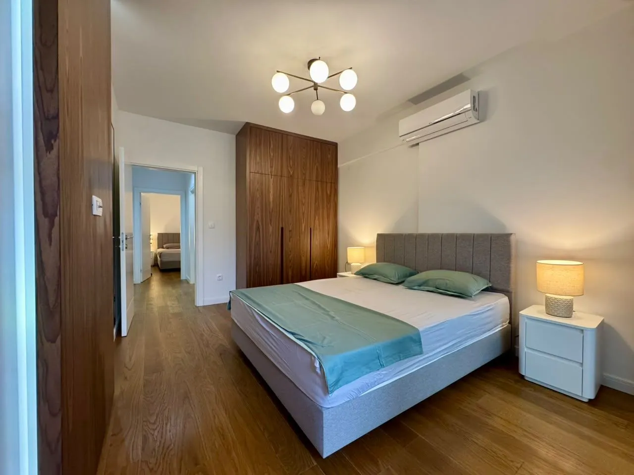 Modern bedroom with a double bed, wooden wardrobe, and laminate flooring.