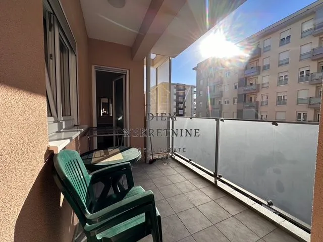 Smaller covered terrace with a table, chairs, and a view of neighboring buildings.