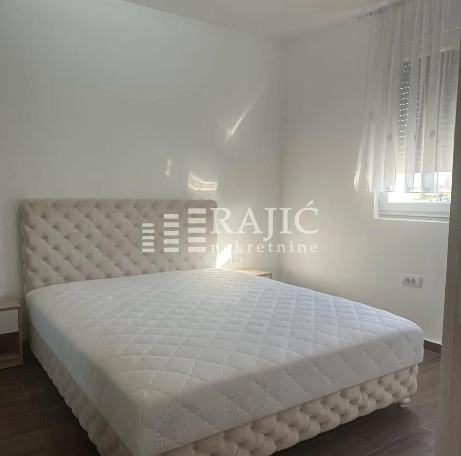 Bright bedroom with a double bed and white walls.