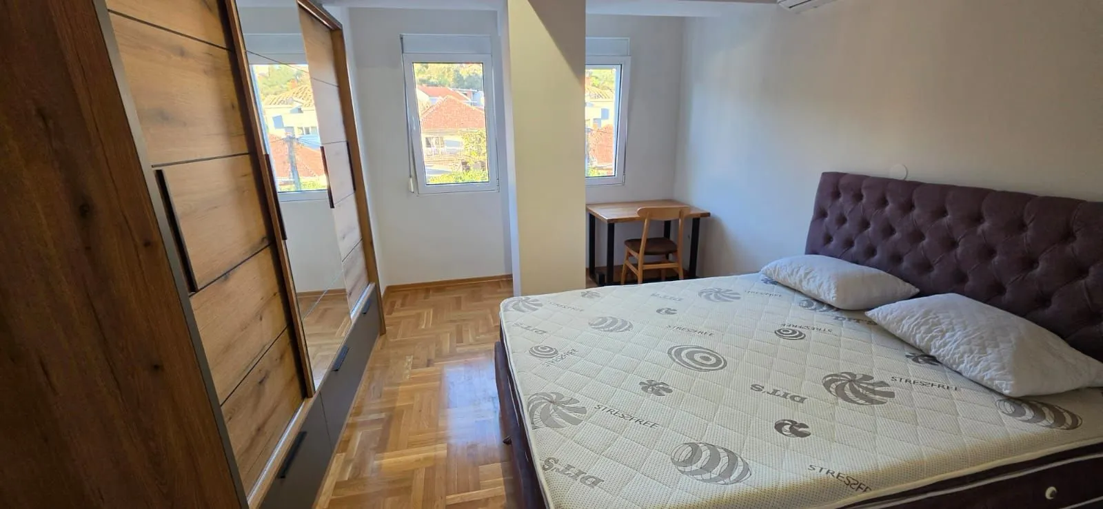 Namještena spavaća soba sa bračnim krevetom, ormarom i radnim stolom.