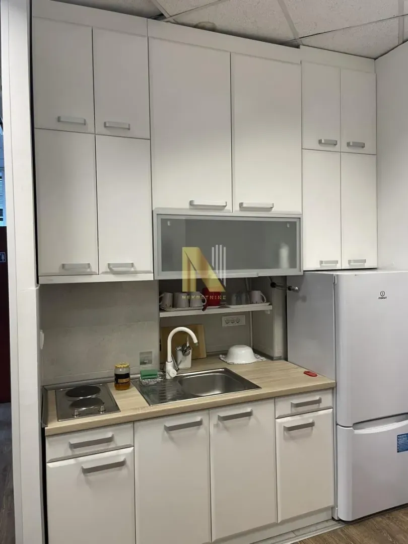 Small white kitchen with sink, built-in cooktop, and refrigerator.