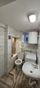 Smaller bathroom with a toilet, washbasin, and water heater. - image 10