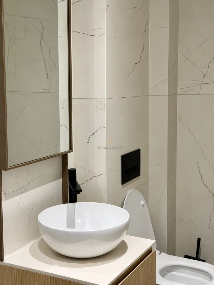 Modern bathroom equipped with a washbasin and marble-effect tiles.