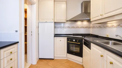 Kitchen equipped with white cabinetry, stove, and refrigerator. - image 3