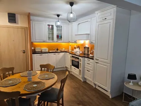 Modern white kitchen with a dining table and wooden floor. - image 6