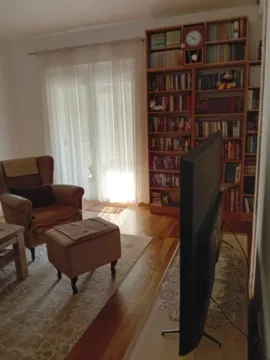 Dnevna soba sa foteljom, policom za knjige i televizorom. - image 3