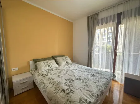 Svijetla spavaća soba sa bračnim krevetom i izlazom na terasu.