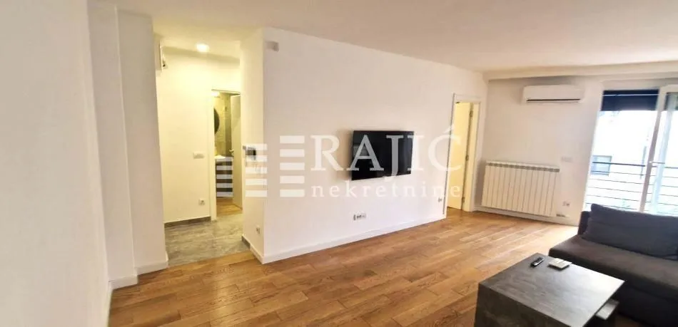 Spacious living room with wooden flooring and a view towards the hallway and terrace.