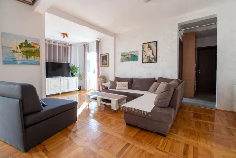 Living room with a sofa set, wooden flooring, and paintings on the wall. - image 2