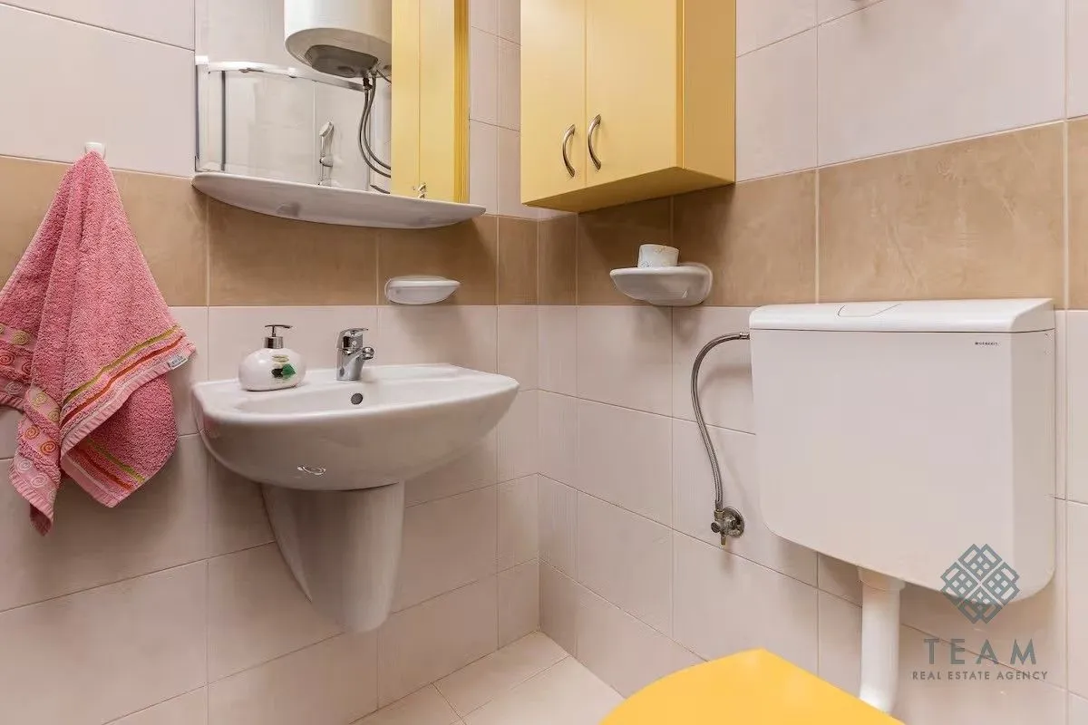 Smaller bathroom with a washbasin, mirror, and toilet.