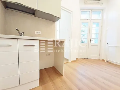 Small kitchen within a bright room with wooden flooring. - image 5