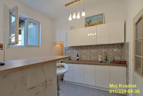 Small kitchen with white cabinets and a breakfast bar. - image 14
