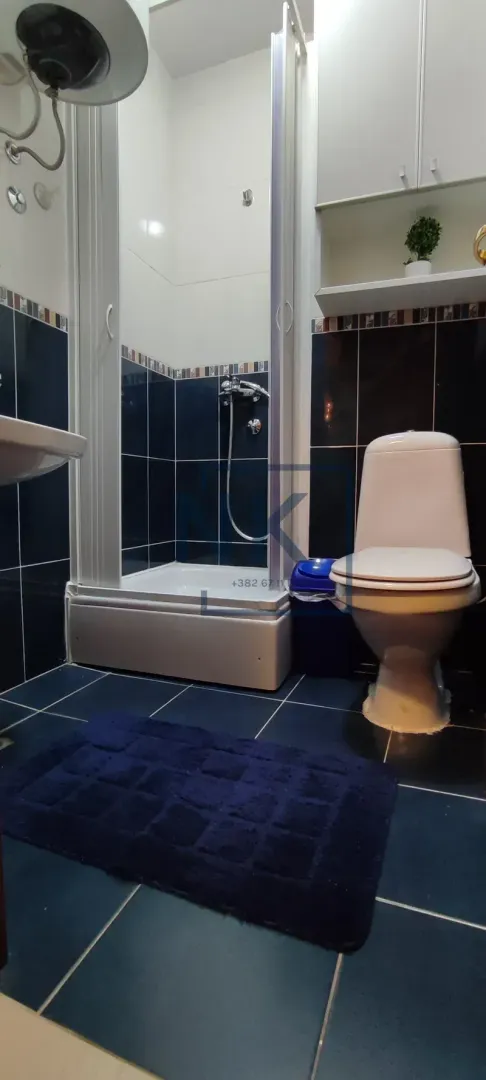 Smaller bathroom with a shower cabin and blue tiles.