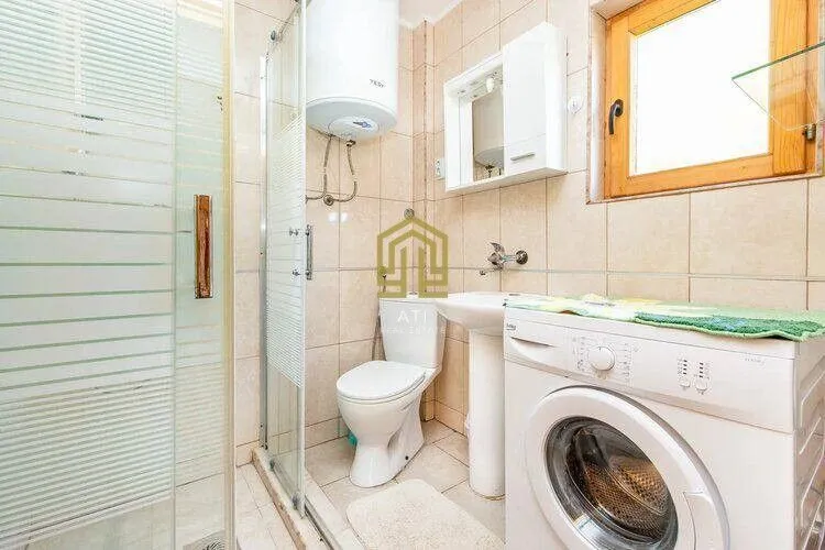 Smaller bathroom with a shower cabin, washbasin, and washing machine.