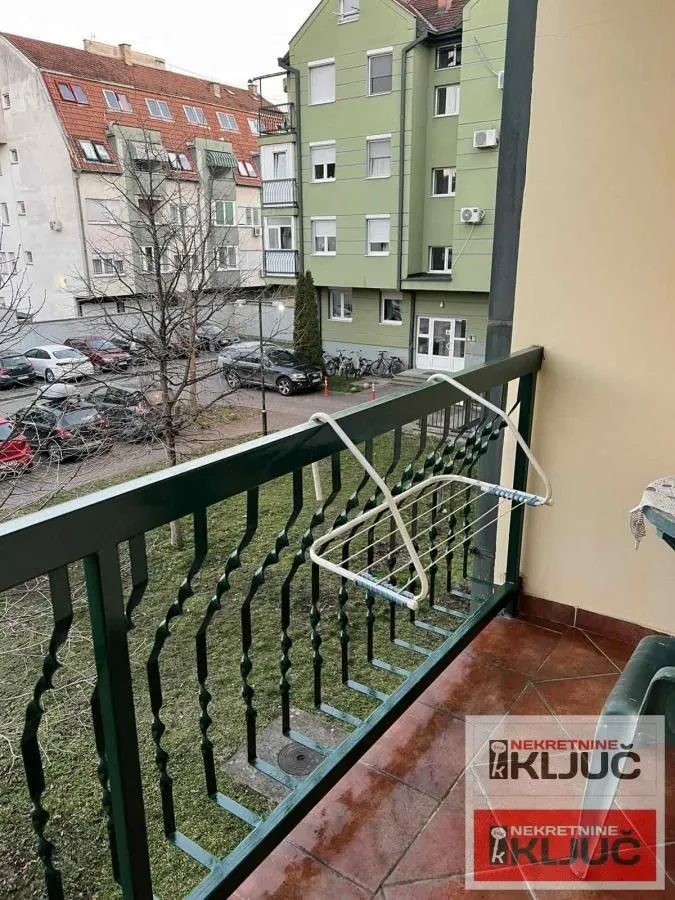 Pogled sa balkona na dvorište, parking i susedne zgrade.