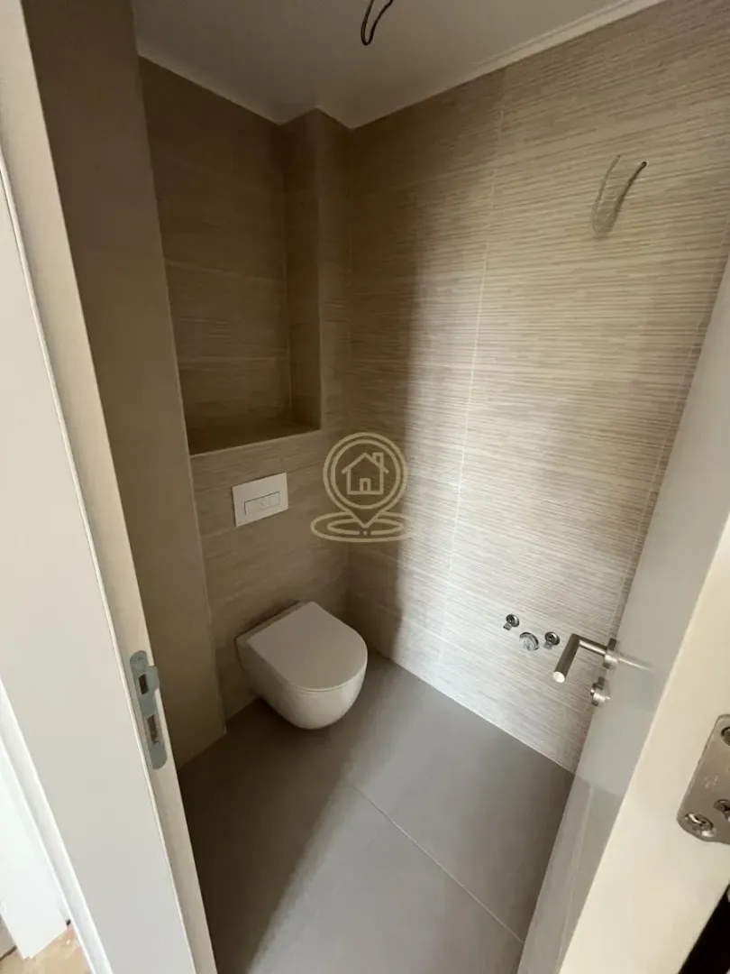 Manje kupatilo sa ugradnom wc šoljom i keramičkim pločicama.