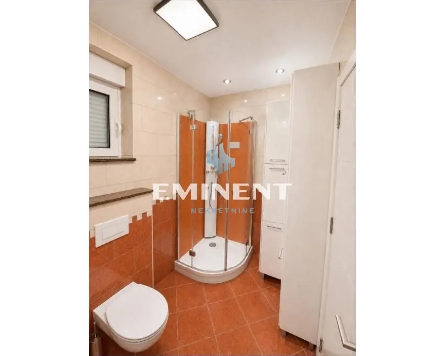Bathroom with a shower cabin, toilet, and white cabinet.