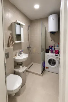 Compact bathroom with a walk-in shower and washing machine. - image 5