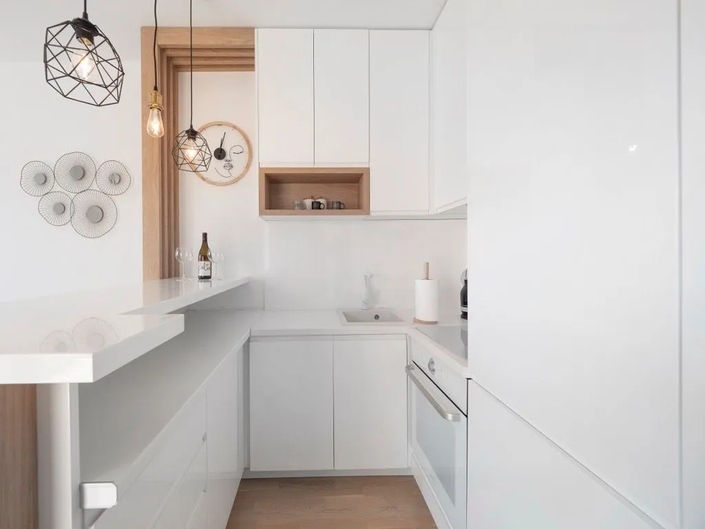 Modern white kitchen with a breakfast bar and built-in appliances.