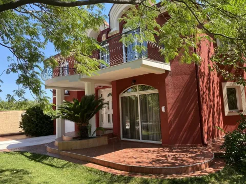 Exterior view of a two-story red house with a tiled terrace and a landscaped yard. - image 2
