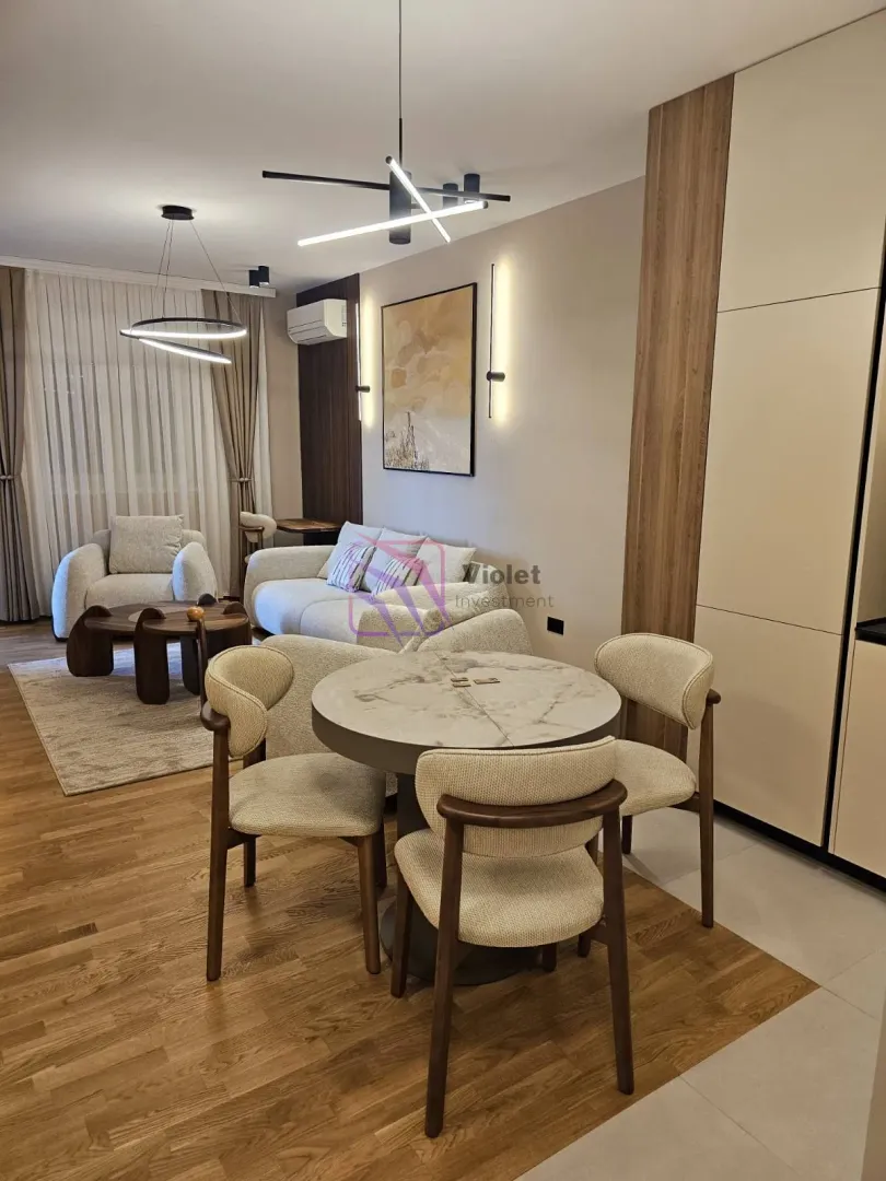 Modern living room with a sofa set, dining table and kitchen elements.