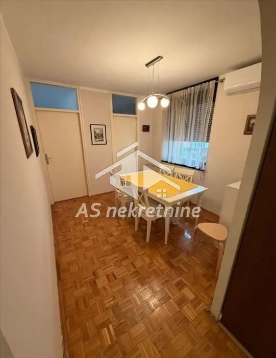 Dining area with a table, chairs, and parquet flooring.