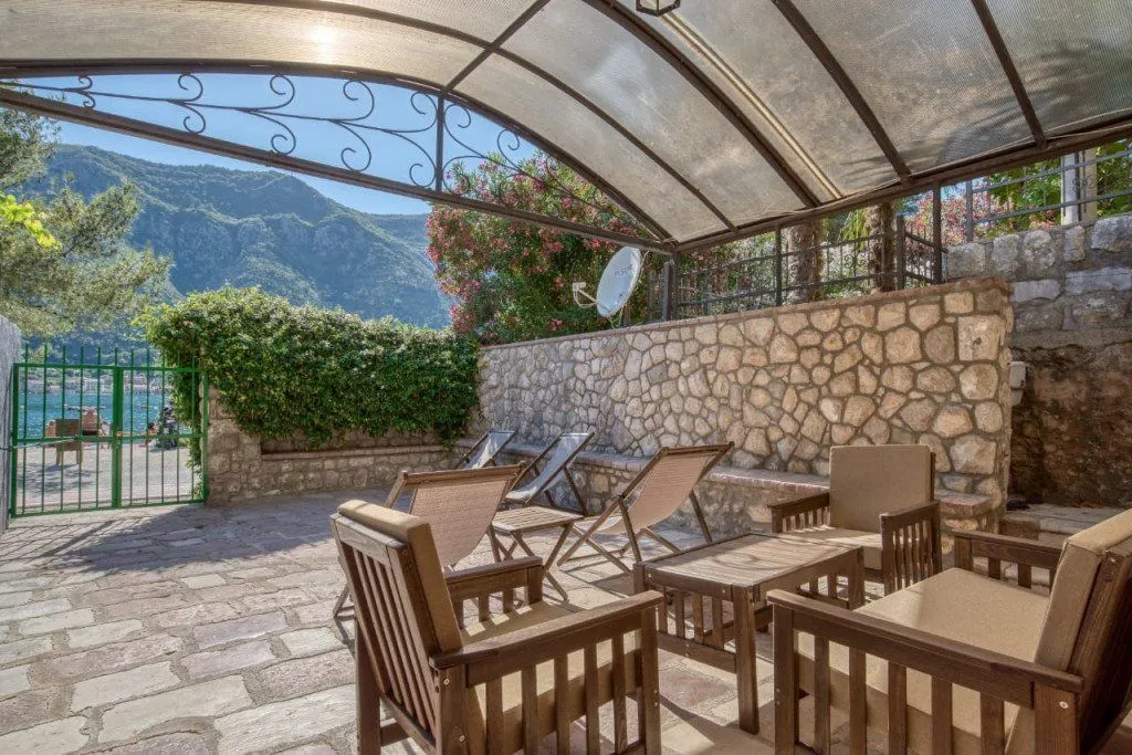 Covered terrace with seating furniture and sun loungers in the yard.