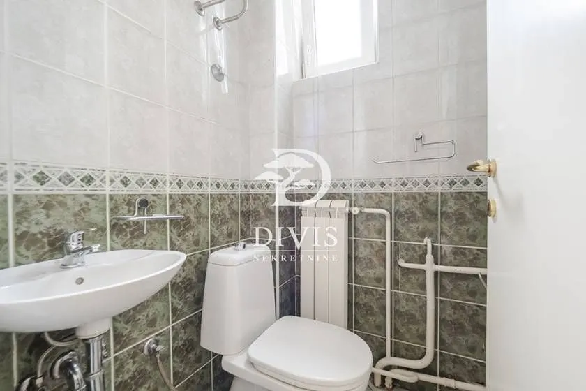 Manje kupatilo obloženo keramičkim pločicama sa umivaonikom i wc šoljom.