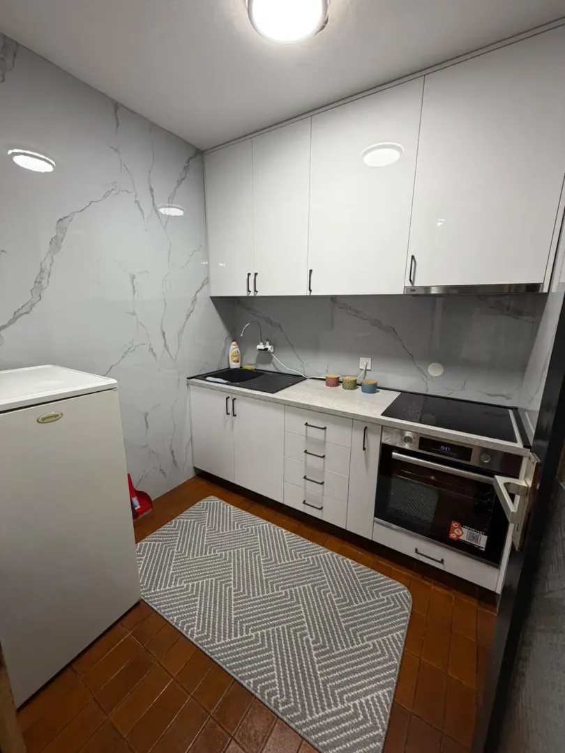 Modern kitchen with white cabinetry and a marble-pattern backsplash.